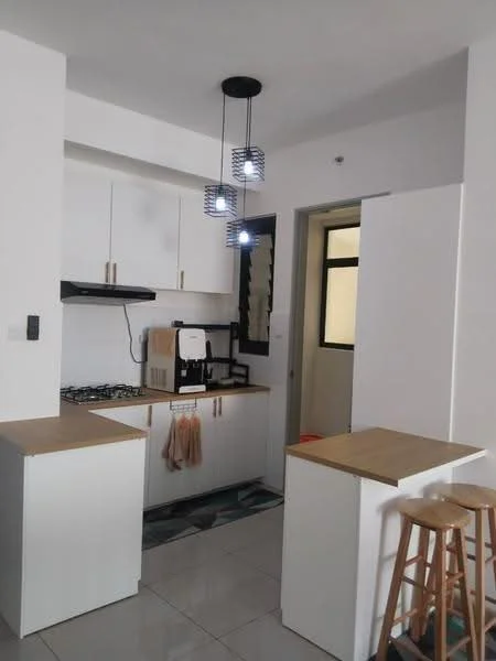 Kitchen features: white cabinetry, wood countertop, stainless-steel gas hob, built-in oven, black range hood, refrigerator, coffee machine, pendant lighting, grey tiled flooring, open layout, bar stools; style: modern.