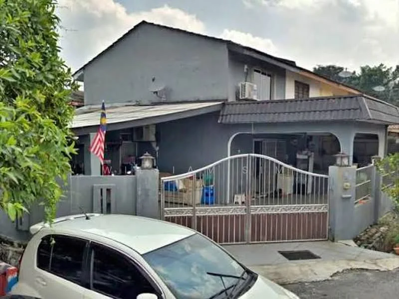 Exterior type: semi-detached house; features: grey painted facade, pitched tile roof, metal gate, front garden area, driveway with concrete surface, air conditioning unit visible, decorative lanterns on gate, flagpole with Malaysian flag, mature trees in vicinity; style: modern.
