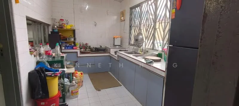 Kitchen features: L-shaped countertop, grey laminate cabinetry, white tiled walls, white tiled flooring, stainless-steel sink, chrome pull-down faucet, built-in gas stove, microwave on countertop, refrigerator, open shelving, various kitchen utensils and containers, window with security bars, yellow shelving unit, floor mat.