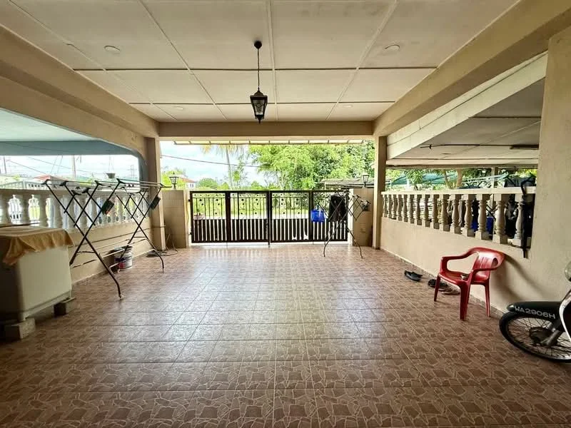 Room features: tiled flooring, ceiling with recessed lighting, open space layout, wooden railing, outdoor view, clothes drying rack, red plastic chair, bicycle, decorative wall with columns, natural light from large openings; style: modern; view: garden.