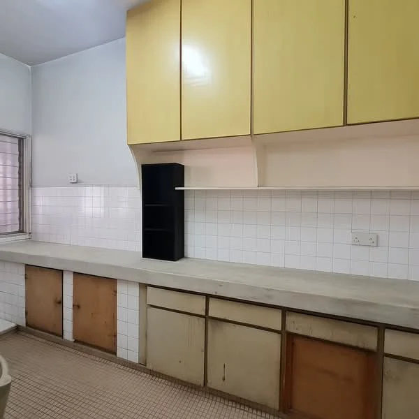 Kitchen features: yellow upper cabinets, white tiled backsplash, concrete countertop, wood lower cabinets with peeling paint, single-bowl stainless-steel sink, wall-mounted shelf, window with grid pattern, tile flooring.