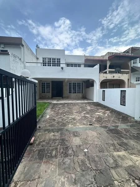 Exterior type: detached bungalow; features: stone-paved driveway, white painted facade, large front windows, covered porch area, manicured lawn, fenced perimeter, two-storey structure, balcony on upper level, clear blue sky, surrounded by greenery; style: modern.