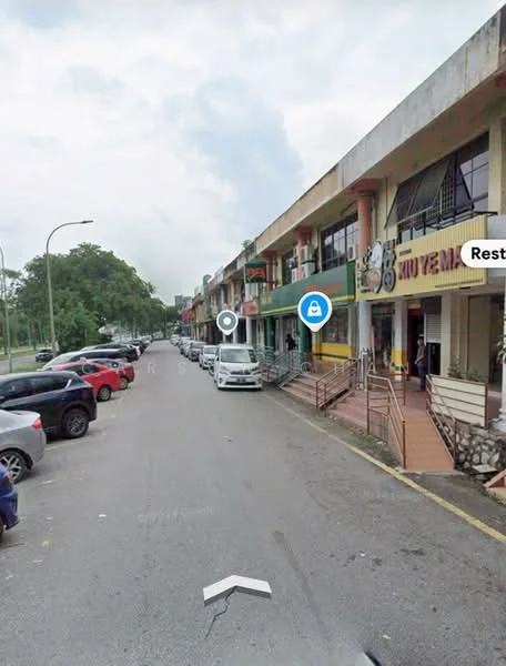 Exterior type: shophouse; features: two-storey building, concrete facade, balconies on upper floor, staircase access to upper floor, multiple parking spaces, street view, surrounded by trees, commercial signage visible; style: modern.