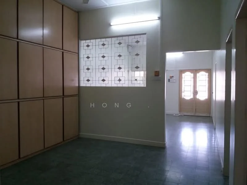 Room features: built-in wooden cabinetry, green tiled flooring, white painted walls, glass block window with decorative pattern, doorway leading to another room, overhead fluorescent lighting.