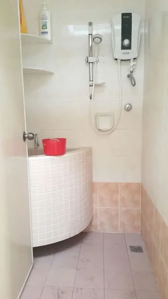 Bathroom features: shower area with glass door, white tiled walls, light beige tiled flooring, wall-mounted shower head, handheld shower attachment, water heater unit, curved vanity with sink, red bucket, shelves for storage; style: modern.