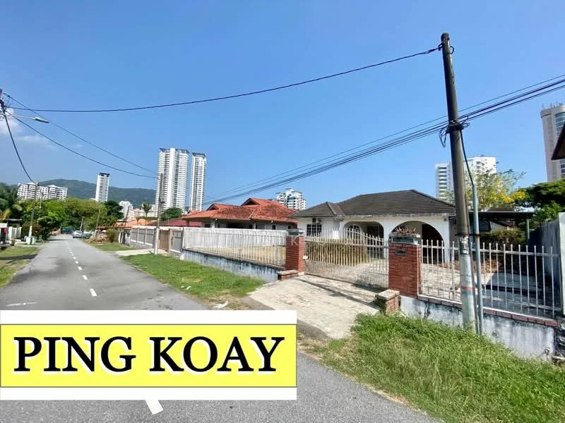 Exterior type: detached bungalow; features: red brick facade, single-storey, manicured lawn, fenced yard, driveway with interlocking pavers, surrounded by mature greenery, adjacent to residential buildings, clear blue sky; style: traditional.