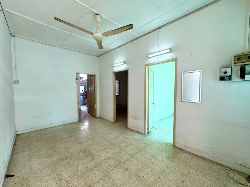 Room features: plain white walls, cement flooring, ceiling fan, fluorescent lighting, two doorways, one wall-mounted electrical panel, no visible furniture, neutral color scheme; style: minimalist.