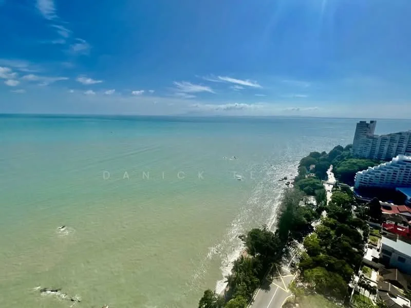 Exterior type: high-rise condominium; features: ocean view, coastal landscape, surrounding greenery, clear blue sky, beachfront, road along the coast; style: modern.