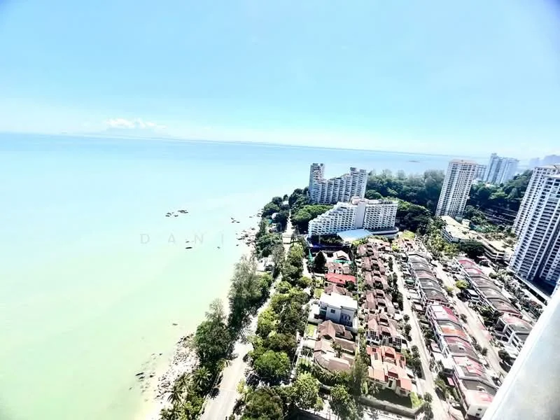 Exterior type: high-rise condominium; features: ocean view, surrounding greenery, residential area, beachfront, multiple high-rise buildings, low-rise houses, coastal road, clear blue sky; style: modern.