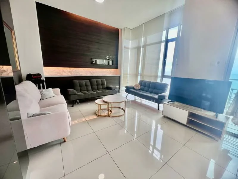 Living features: white walls, dark wood accent wall, large floor-to-ceiling windows, grey fabric 3-seater sofa, grey fabric 2-seater sofa, round coffee table with gold base, white TV console, large flat-screen TV, marble flooring, sheer curtains, decorative wall shelf; style: modern; view: sea.