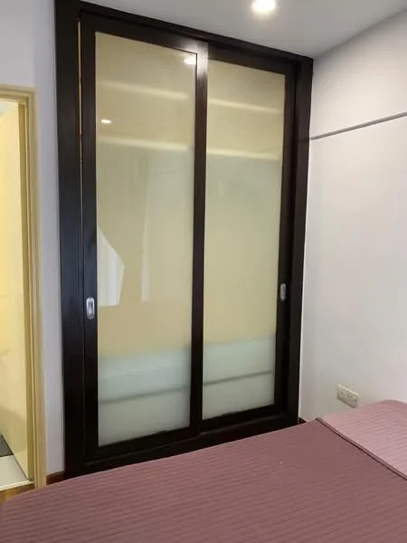 Room features: sliding glass door with frosted panels, dark wood frame, light-colored wall, bed with maroon bedspread, wall-mounted electrical outlet; style: modern.