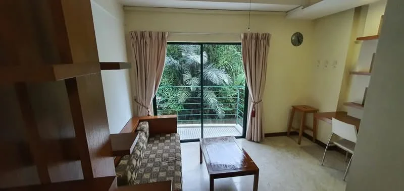 Living features: sofa with patterned upholstery, wooden coffee table, floor-to-ceiling sliding glass door, curtains, wall-mounted clock, wooden shelving unit, study desk, white chair, light-colored walls, marble flooring; style: modern; view: garden.