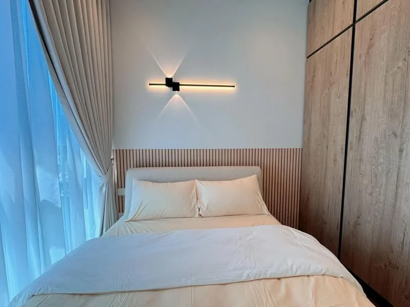 Bedroom features: queen-size bed with beige bedding, wooden headboard, wood panel accent wall, built-in wardrobe with wood finish, floor-to-ceiling windows, sheer curtains, recessed wall lighting, light wood flooring; style: modern.