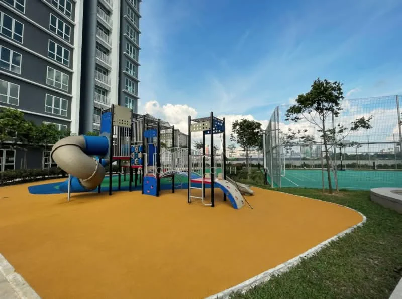 Exterior type: high-rise condominium; features: children's playground with slides and climbing structures, rubberized safety flooring in yellow, manicured lawn, surrounding trees, fenced sports court in background, clear blue sky; style: modern.
