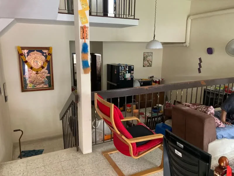 Room features: staircase with metal railing, decorative wall art, refrigerator, sofa, armchair, ceiling light fixture, wall-mounted fan, open space layout, tile flooring, wall with light paint, decorative items on shelves; style: modern.