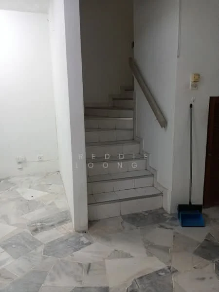 Room features: marble flooring, white painted walls, staircase with handrail, light switch, cleaning supplies, corner broom, neutral color scheme.