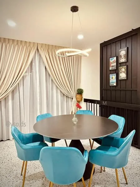 Dining features: round dining table, dark wood table surface, 6 upholstered dining chairs in light blue, golden wooden legs on chairs, pendant light fixture with circular design, floor-to-ceiling curtains in cream, decorative wall with framed artwork, plant in decorative pot, textured wall paneling, speckled flooring; style: modern.
