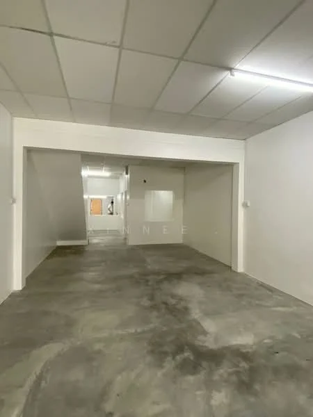 Room features: white painted walls, concrete flooring, drop ceiling, fluorescent lighting, open layout, staircase visible in background, no visible windows or doors; style: minimalist.