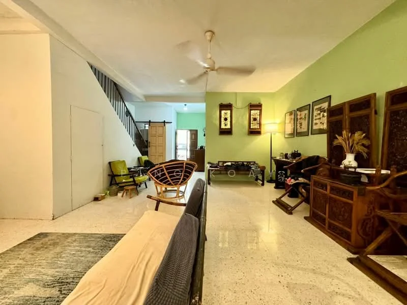 Living features: green painted walls, white ceiling, ceiling fan, polished concrete flooring, sofa, wooden coffee table, decorative wall art, wooden side tables, area rug with geometric pattern, wooden rocking chair, wooden armchair, staircase in background; style: traditional.
