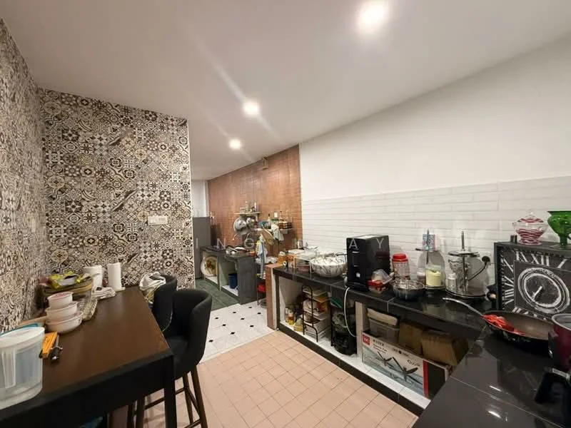 Kitchen features: black countertop, white tiled backsplash, decorative patterned wall tiles, wooden bar table with stools, stainless-steel sink, built-in cabinets, freestanding stove, microwave, refrigerator, open shelving, various kitchen appliances, floor tiles in light color, wall-mounted lighting, laundry area visible in background; style: modern.