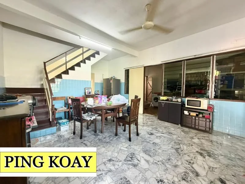 Living features: marble flooring, white painted walls, ceiling fan, wooden dining table with chairs, kitchenette area with blue tiled backsplash, large windows with natural light, staircase leading to upper floor, various household items on the floor, microwave on countertop, small cabinet, open layout.
