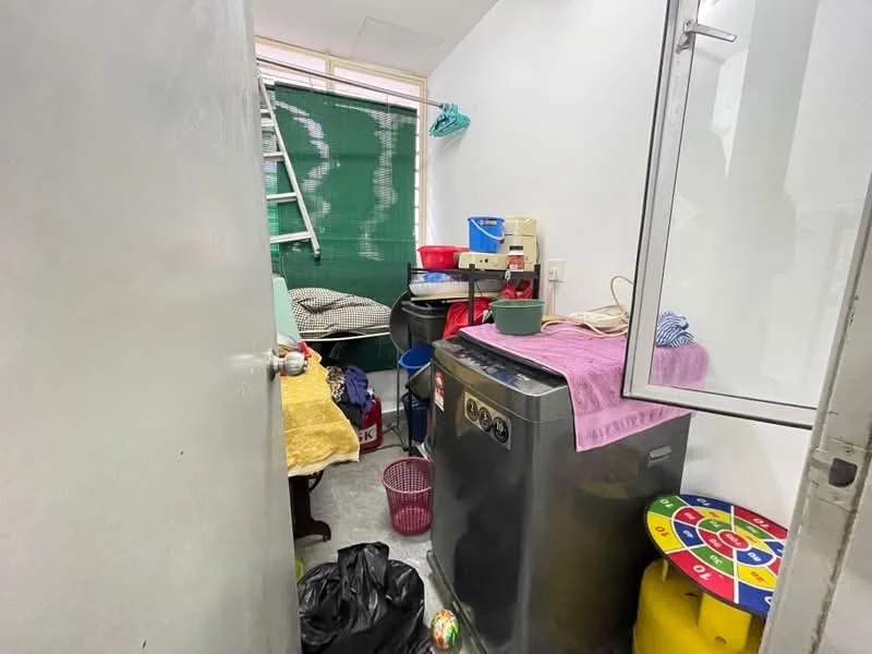 Laundry features: front-load washing machine, plastic laundry basket, wooden table, plastic trash bag, ladder, green curtain, various storage containers, colorful game board.