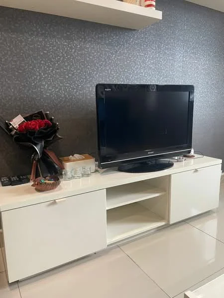 Living features: white TV console, black flat-screen TV, grey accent wall, polished tile flooring, decorative flowers in vase, shelves above TV console, remote controls, glass coasters; style: modern.
