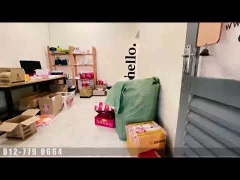 Room features: light-colored walls, tile flooring, wooden shelving unit, boxes and packaging materials, green storage bag, desk with computer, open doorway, minimal decor; style: minimalist.