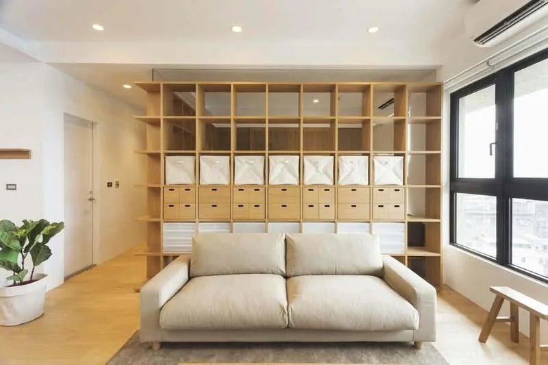 Living features: 3-seater fabric sofa in beige, wooden shelving unit with storage boxes, floor-to-ceiling windows, light wood flooring, recessed downlights, indoor plant in white pot, air conditioning unit, neutral wall color; style: modern; view: city.