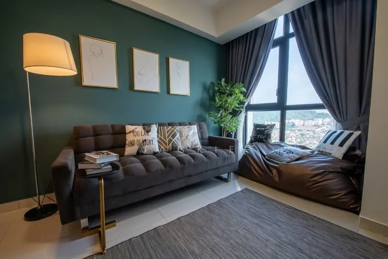 Living features: grey fabric sofa, floor lamp, decorative throw pillows, green accent wall, floor-to-ceiling windows, curtains, bean bag chair, area rug, coffee table, framed artwork on walls; style: modern; view: city.