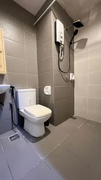 Bathroom features: grey tiled walls, grey tiled flooring, one-piece toilet, handheld shower, wall-mounted shower head, sink with cabinet, toilet paper holder, drainage grate; style: modern.