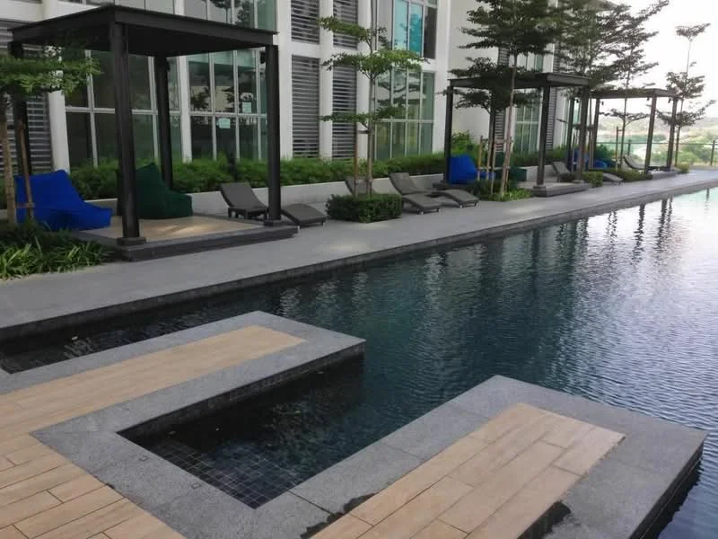 Exterior type: swimming pool deck; features: infinity pool, pool deck with loungers, landscaped greenery, paved walkway, shade structures, outdoor seating, water feature, surrounding trees; style: modern.