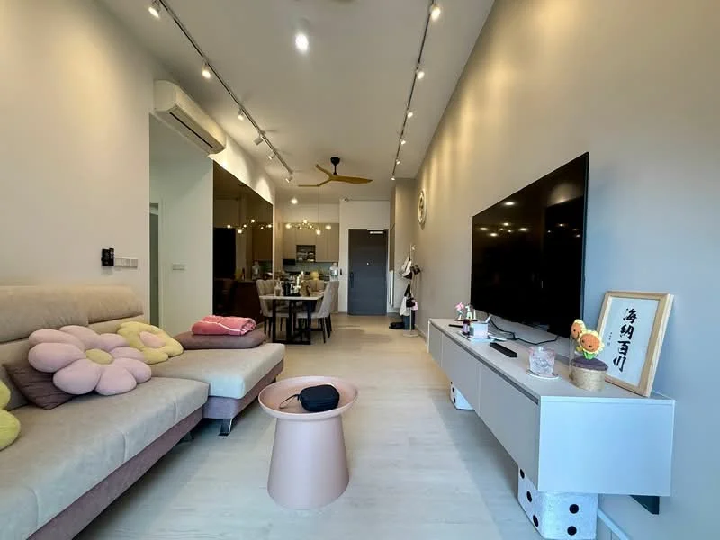 Living features: light grey walls, wooden flooring, 5-blade ceiling fan with light, sofa with floral pattern in beige and pink, pink round coffee table, wall-mounted TV, TV console in white, decorative artwork on console, open layout to kitchen, recessed lighting, large window with natural light; style: modern. Kitchen features: open kitchen layout, dark cabinetry, stainless-steel appliances, kitchen island with seating, pendant lighting over island; style: modern.