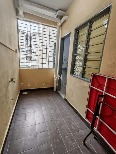 Room features: grey tiled flooring, cream painted walls, metal window grilles, single window with vertical bars, doorway leading to another room, foldable red table, black folding chair.