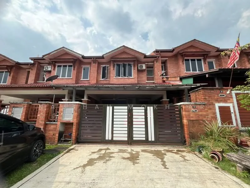 Exterior type: linked terrace house; features: red brick facade, white painted accents, flat roof, double-storey, manicured lawn, car porch with awning, visible air conditioning units, flagpole with Malaysian flag, paved driveway, garden area with plants; style: modern.