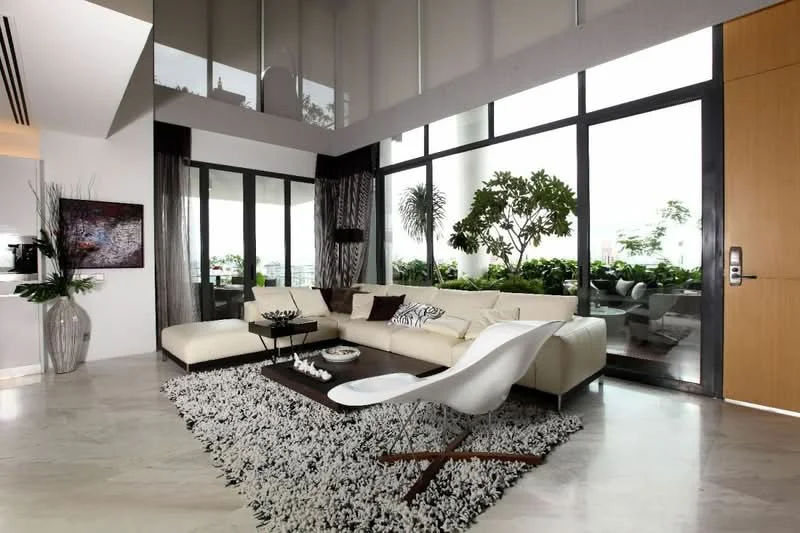 Living features: cream leather sectional sofa, black and white decorative cushions, white coffee table, area rug with geometric pattern, floor-to-ceiling windows, sheer curtains, dark wood door, decorative wall art, potted plants, marble flooring, recessed downlights, indoor plants; style: modern; view: garden.