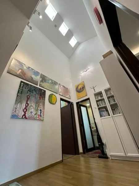 Room features: white painted walls, wooden flooring, high ceiling, skylights, framed artwork on walls, built-in cabinets, doorway leading to another room, decorative lighting, area rug, shelves with books; style: modern.