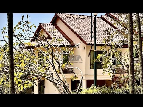Exterior type: detached bungalow; features: red tiled roof, cream painted facade, wooden window frames, balconies with railings, manicured landscaping, mature trees, outdoor lighting, two-storey structure; style: modern.