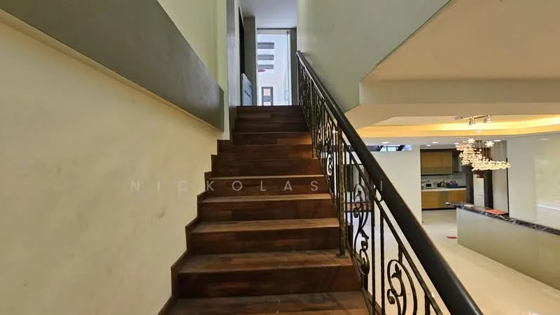 Room features: wooden staircase, metal railing, cream painted walls, grey accent wall, recessed lighting, open space at the top of the stairs, view into kitchen area; style: modern.