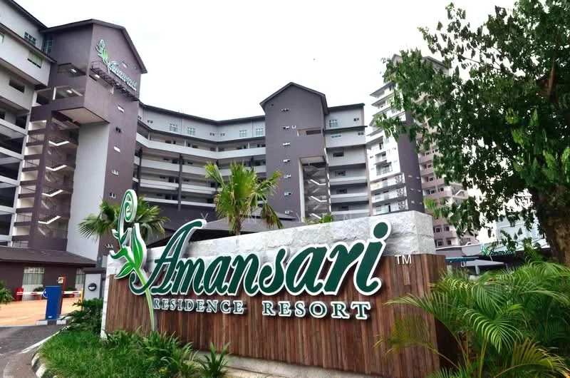 Exterior type: resort condominium; features: multi-storey building, modern facade with grey and white colors, landscaped garden with palm trees, prominent signage with the name 'Amansari Residence Resort', parking area visible, surrounding greenery; style: modern.