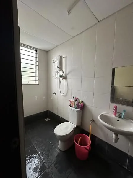 Bathroom features: white tiled walls, black tile flooring, toilet, sink with pedestal, mirror above sink, shower with wall-mounted faucet, window with metal grille, shower curtain rod, pink bucket, toiletries on sink.