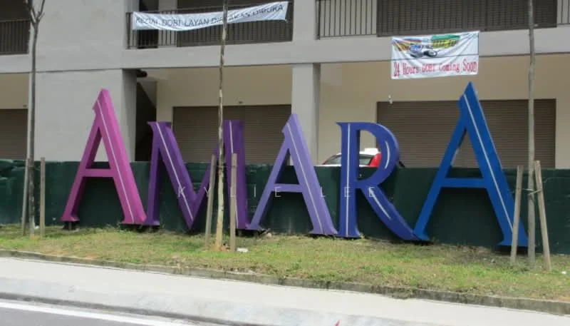 Exterior features: large signage with the word 'AMARA', purple and blue color scheme, surrounding greenery, paved walkway, fenced area, two-story building in background; style: modern.