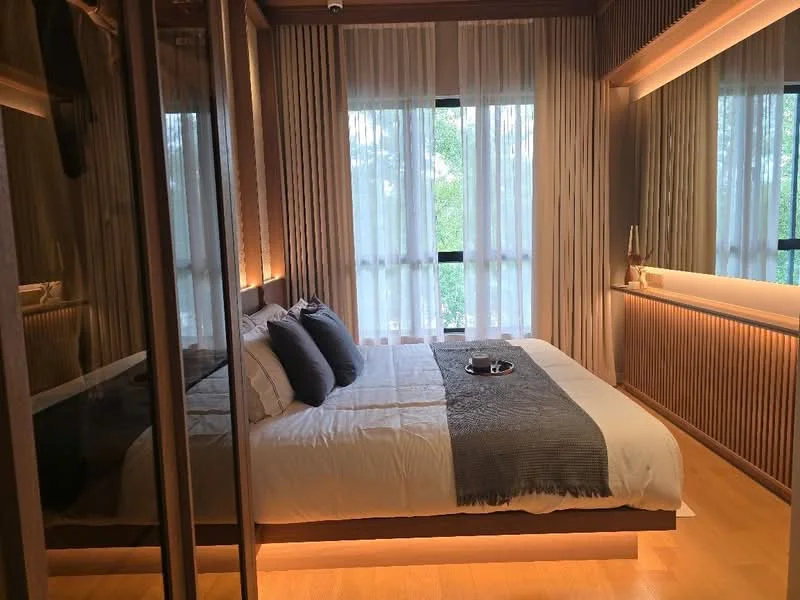 Bedroom features: king-size bed with white bedding, upholstered headboard, two bedside lamps, built-in wardrobe with mirrored doors, wood paneling on walls, floor-to-ceiling windows, sheer curtains, wooden flooring, recessed lighting, decorative wall lighting; style: modern; view: garden.