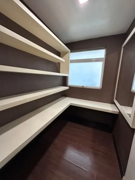 Room features: built-in shelving, light-colored shelves, dark wood flooring, window with natural light, brown painted walls, corner layout, mirror on wall; style: modern.