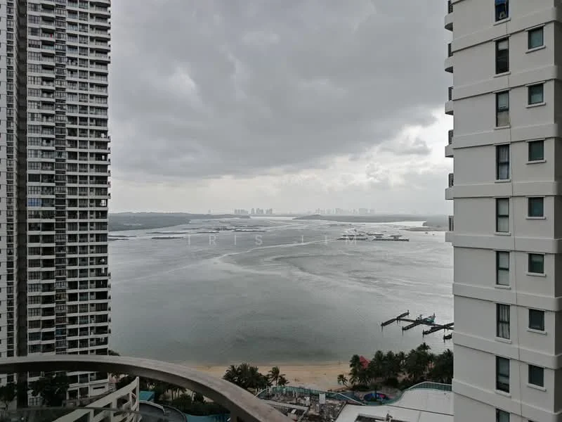 Exterior type: high-rise condominium; features: waterfront view, city skyline in background, surrounded by water, balcony visible, multiple high-rise buildings, cloudy sky; style: modern.