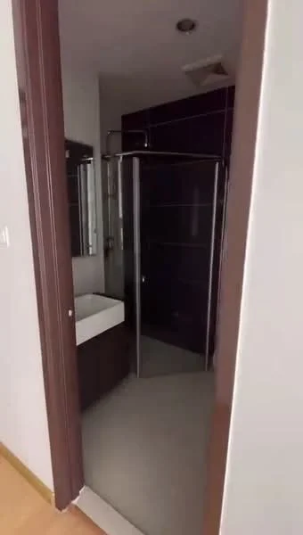 Bathroom features: glass shower enclosure, rain shower head, wall-mounted faucet, single-sink vanity with cabinet, dark tile walls, light tile flooring, mirror above sink, recessed lighting; style: modern.