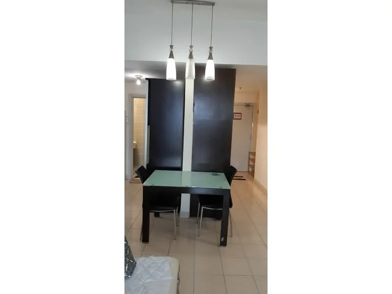 Dining features: glass dining table, 4 black dining chairs, pendant lighting with three fixtures, cream tiled flooring, white walls, partition wall, open layout, doorway leading to hallway; style: modern.