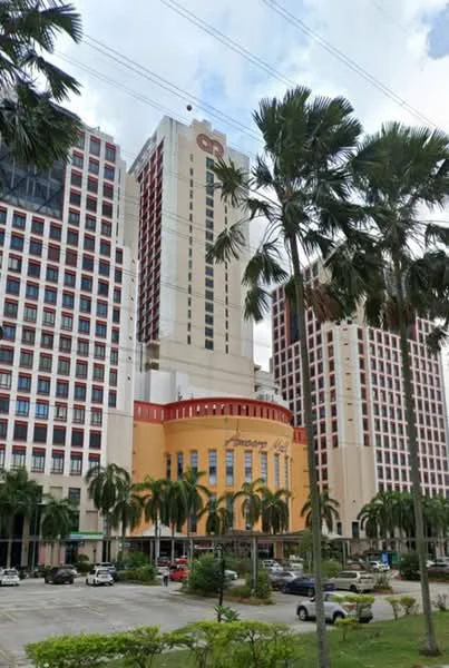 Exterior type: high-rise condominium; features: glass curtain wall, red accent facade, palm trees in foreground, manicured lawn, multiple storeys, parking lot with cars, surrounded by greenery; style: modern.