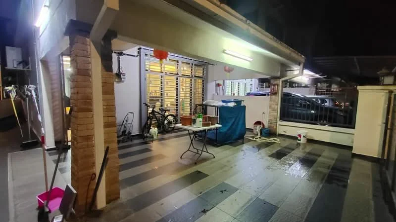 Exterior type: linked terrace house; features: paved flooring with alternating black and grey tiles, covered porch area, outdoor lighting fixtures, bicycle parked, table with chairs, water hose visible, decorative lanterns, utility area with storage, fenced perimeter, nighttime lighting; style: modern.