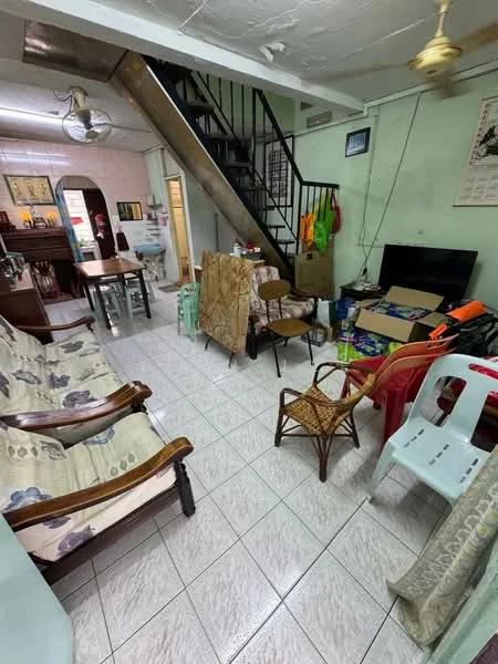 Living features: white painted walls, tiled flooring, ceiling fan, sofa with floral upholstery, wooden armchair, plastic chairs, dining table, television, staircase, decorative wall art, boxes and miscellaneous items.